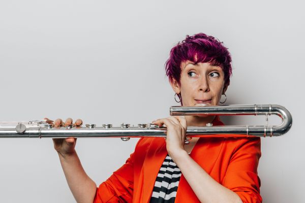 Woman playing with long flute on white background.