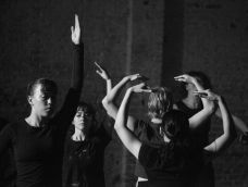Black and white photo of dancers mid-performance with arms reaching up.