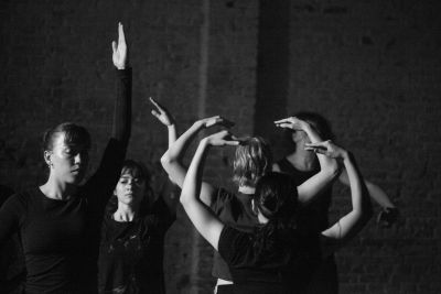 Black and white photo of dancers mid-performance with arms reaching up.