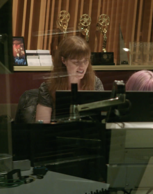 Woman sitting in front of a monitor in recording studio.