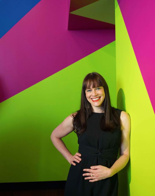 Woman standing in front of geometric colourful mural.