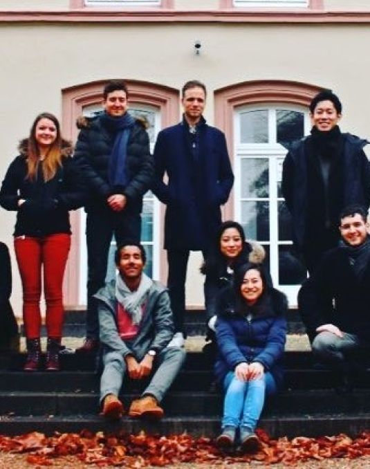 A large group of people sit and stand on outdoor steps.