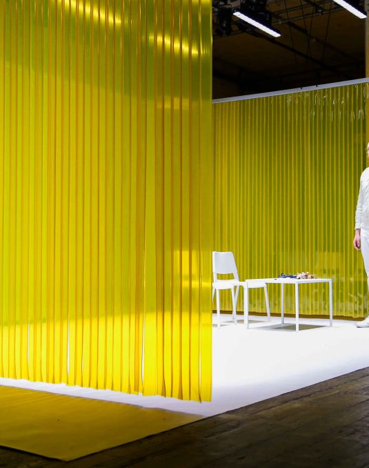 Stage performance with clear yellow curtain and an actor dressed in white.
