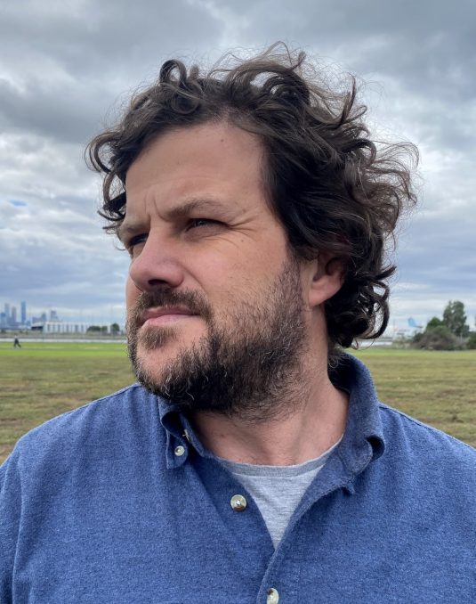 Portrait of Dr Nicholas Mangan. A man wearing a blue shirt.