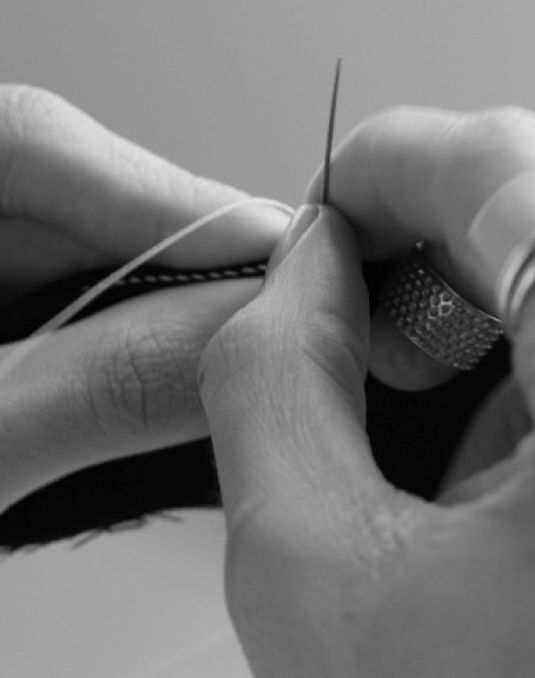 Hands holding fabric and a needle with thread. 