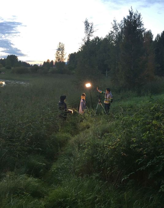 Film shoot in the middle of a grassy field.