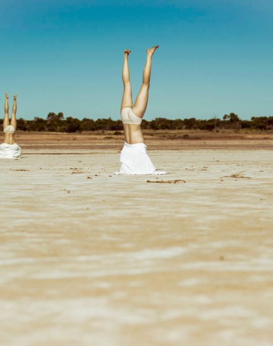 Two dancers in handstand positions on a desert lanscape.