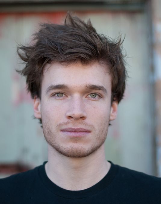 Portrait of man with short brown hair and green eyes.