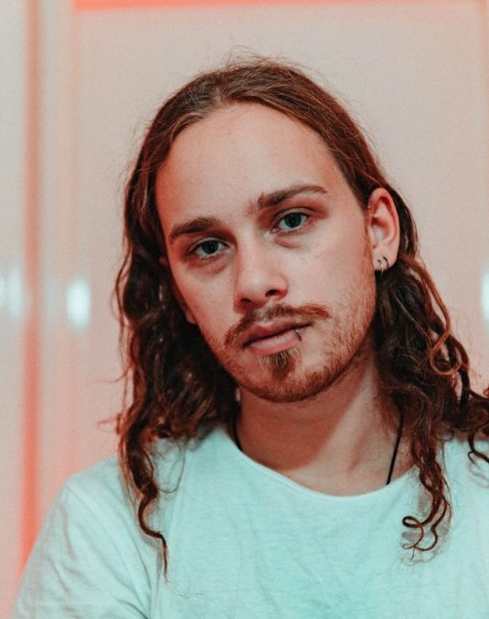 Headshot of long-haired artist facing at camera