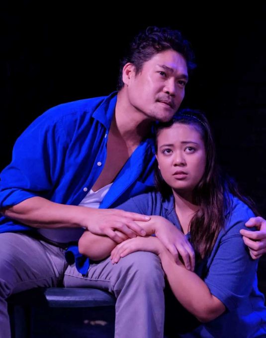 Two actors embracing on stage. 