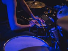 Pair of hands holding drumsticks rested on a drumset.