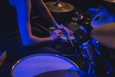 Pair of hands holding drumsticks rested on a drumset.