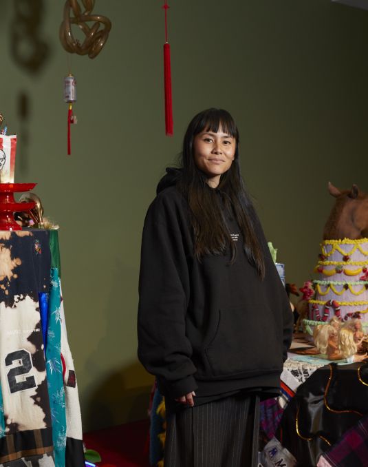 Woman posing at camera with art installation in backgorund.