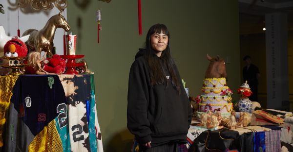 Woman posing at camera with art installation in backgorund.