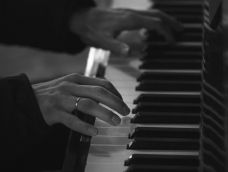 Black and white imagee of hands playing piano.