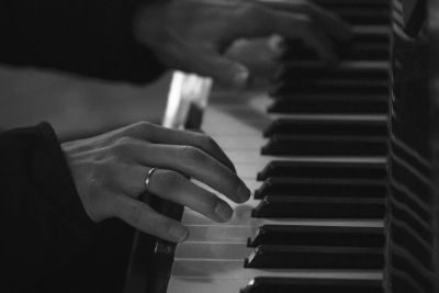 Black and white imagee of hands playing piano.